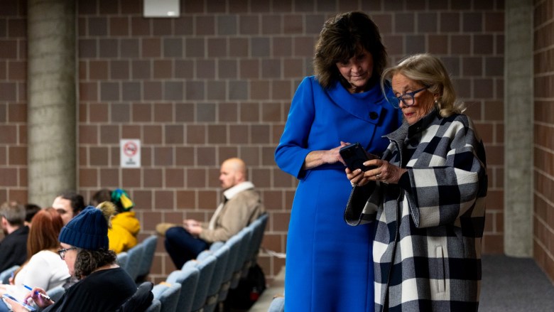 Two people converse at the back of an auditorium