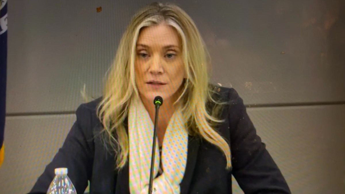 A woman speaks into a microphone at a board meeting