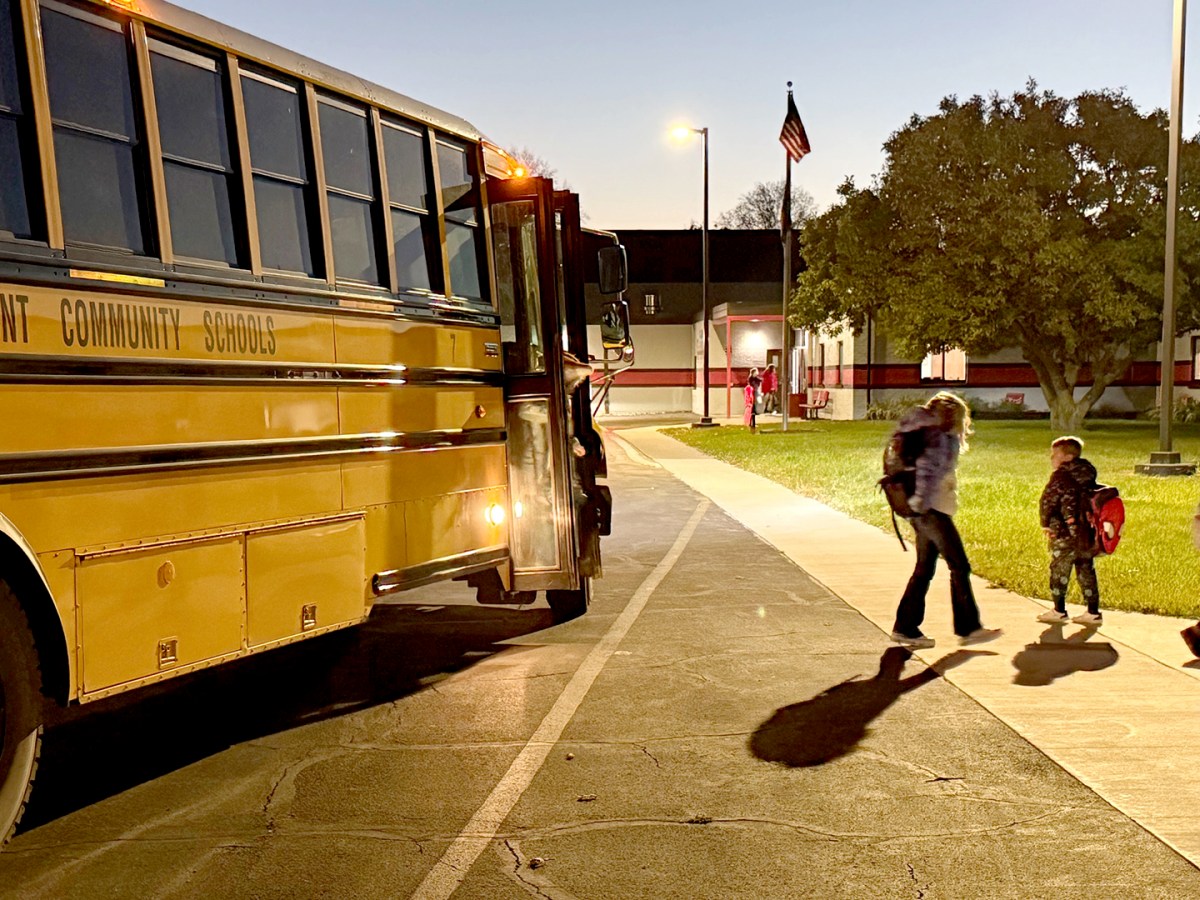Students walk out of the bus in the early morning hours. 