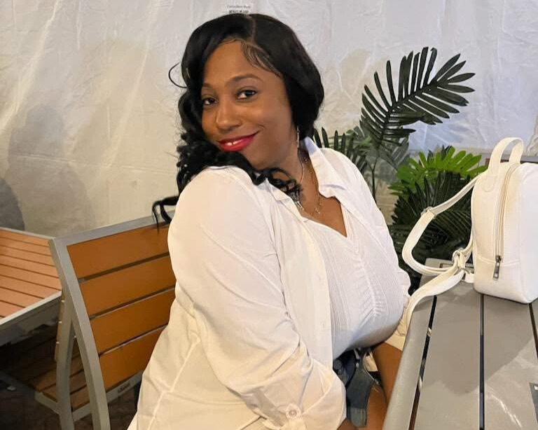 Latricia Green, wearing a white shirt, sits at a table.
