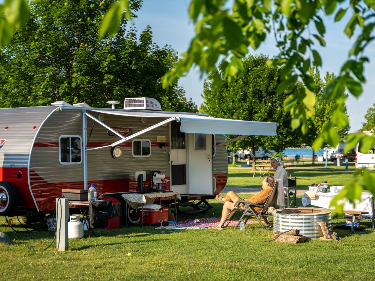 People sit around a camper