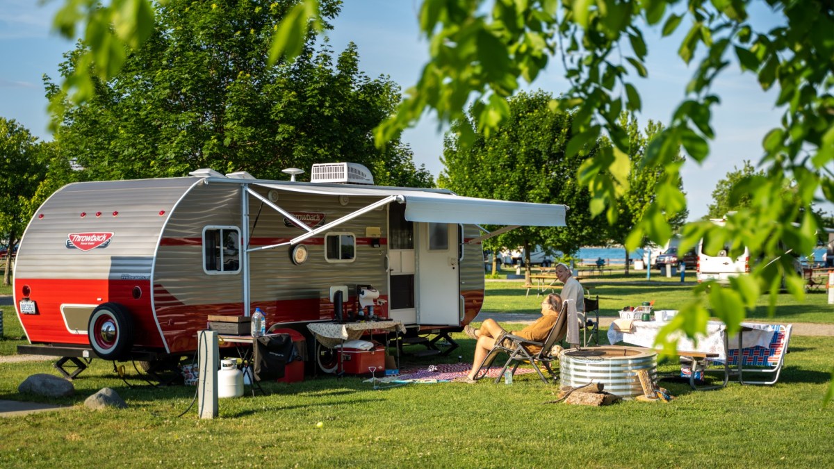 People sit around a camper