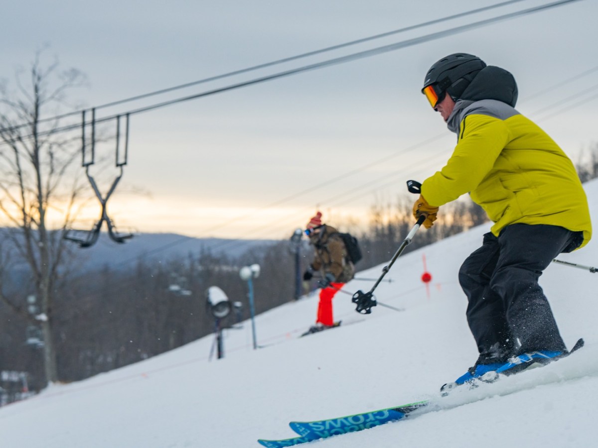 Skiers ski down a snowy hill