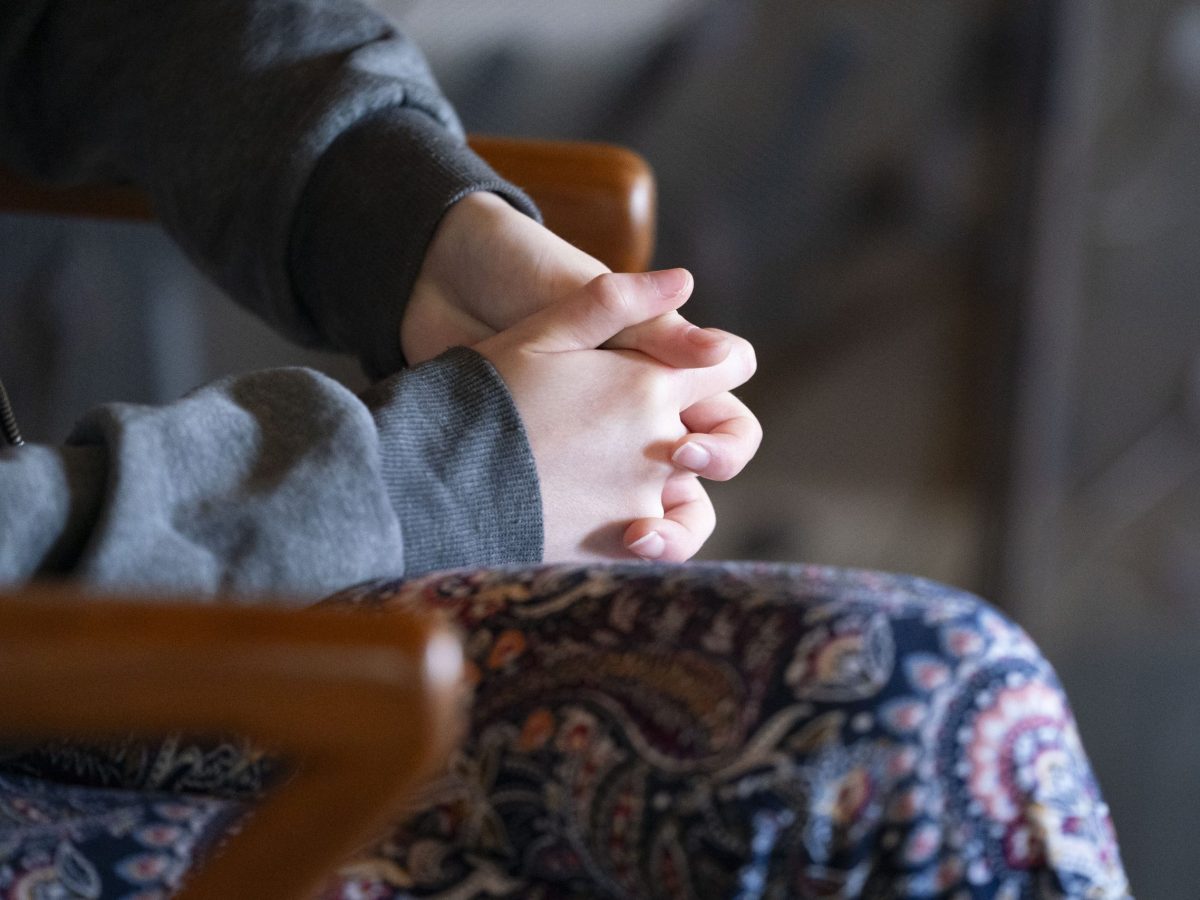closeup of hands folded in a seated person's lap