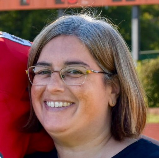 Headshot with a woman facing slightly left and smiling. A companion's shoulder is seen in background.