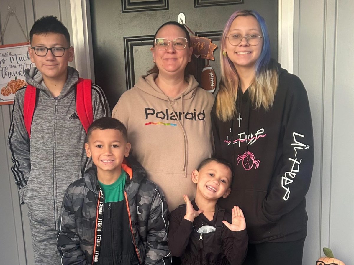 A mother surrounded by four children poses in the doorway of a house.