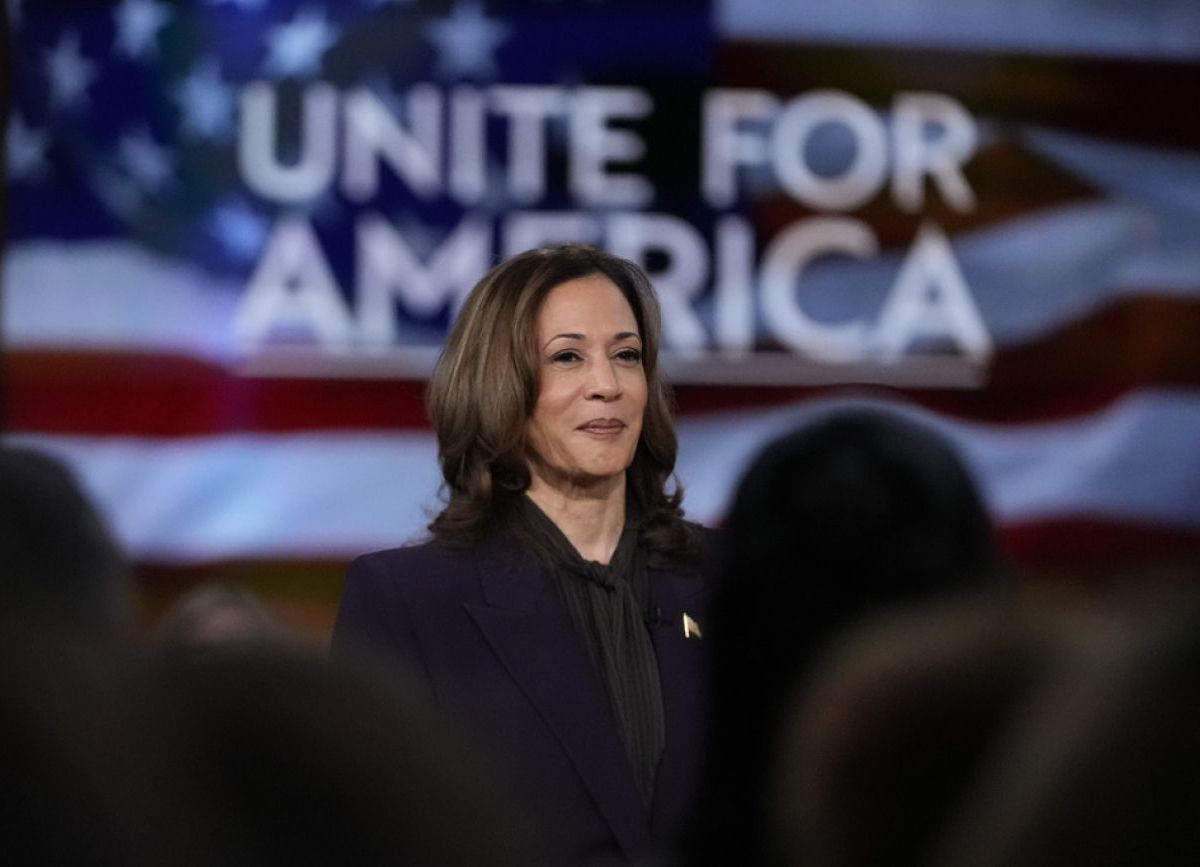 Kamala Harris on the stage, behind the stage says Unite for America
