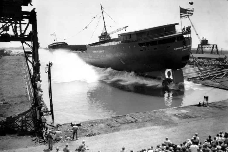 A black-and-white photo of the SS Edmund Fitzgerald on the dock. People are also on the dock.