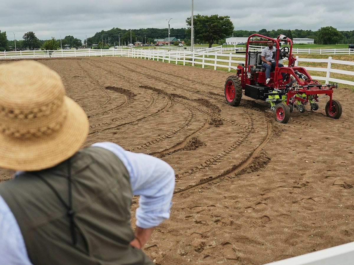 A person has their back to the camera. They are watching the electric tractor. 