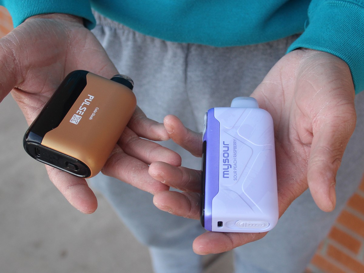 Someone holding vape cartridges in their hands. 