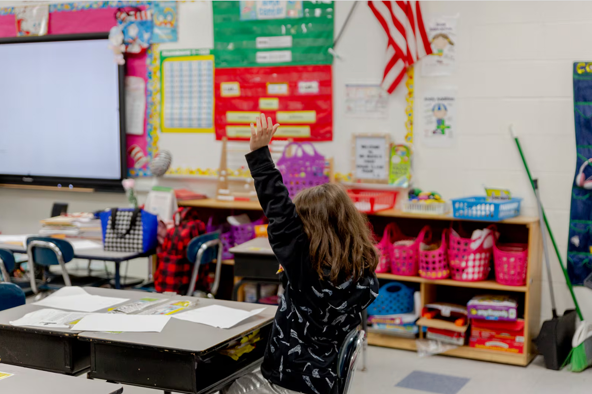 A child raising their hand in a classroom