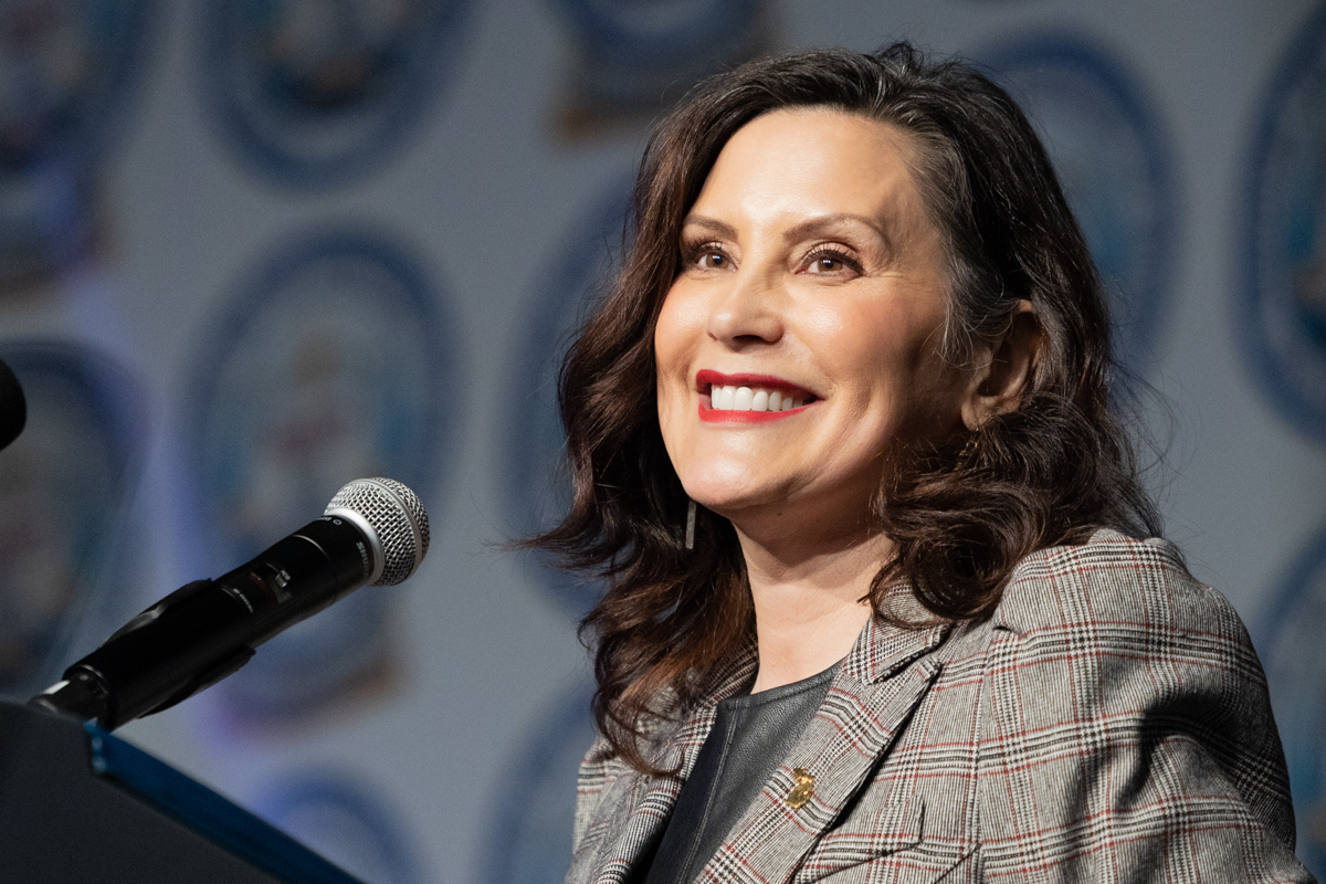 Gov. Gretchen Whitmer smiling while standing in front of a microphone.