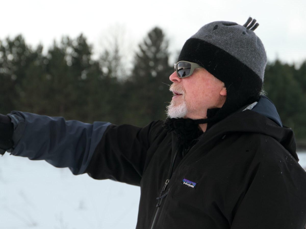 A man stands and points in a snowy field