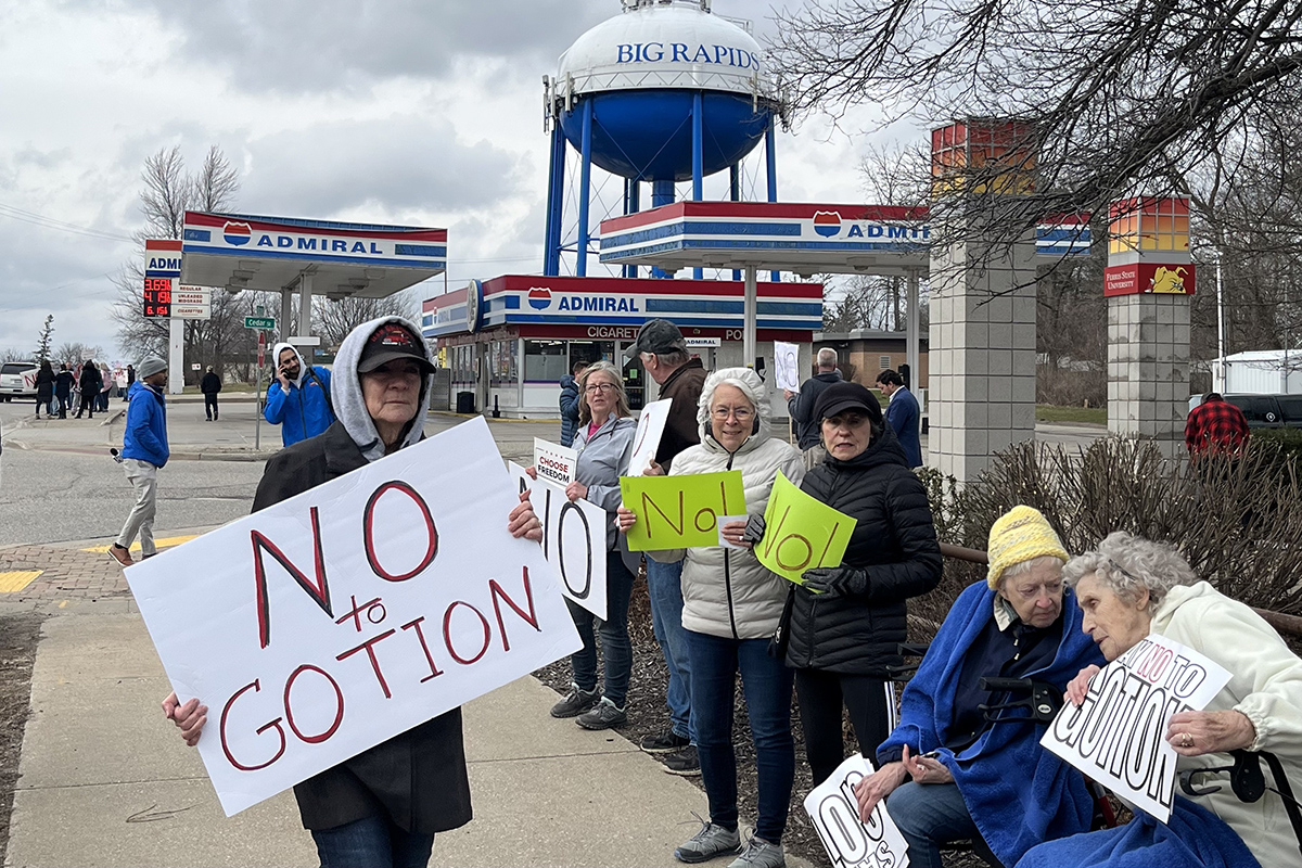 Marianne Pitts, center in white jacket, joined several hundred people in Big Rapids, lining both sides of South State Street to protest a planned Gotion battery component factory.