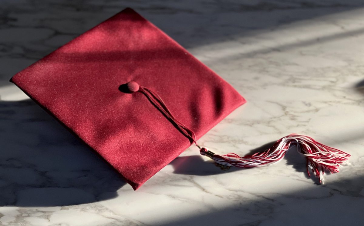 dramatic shot of a red graduation cap and tassel on marble surface