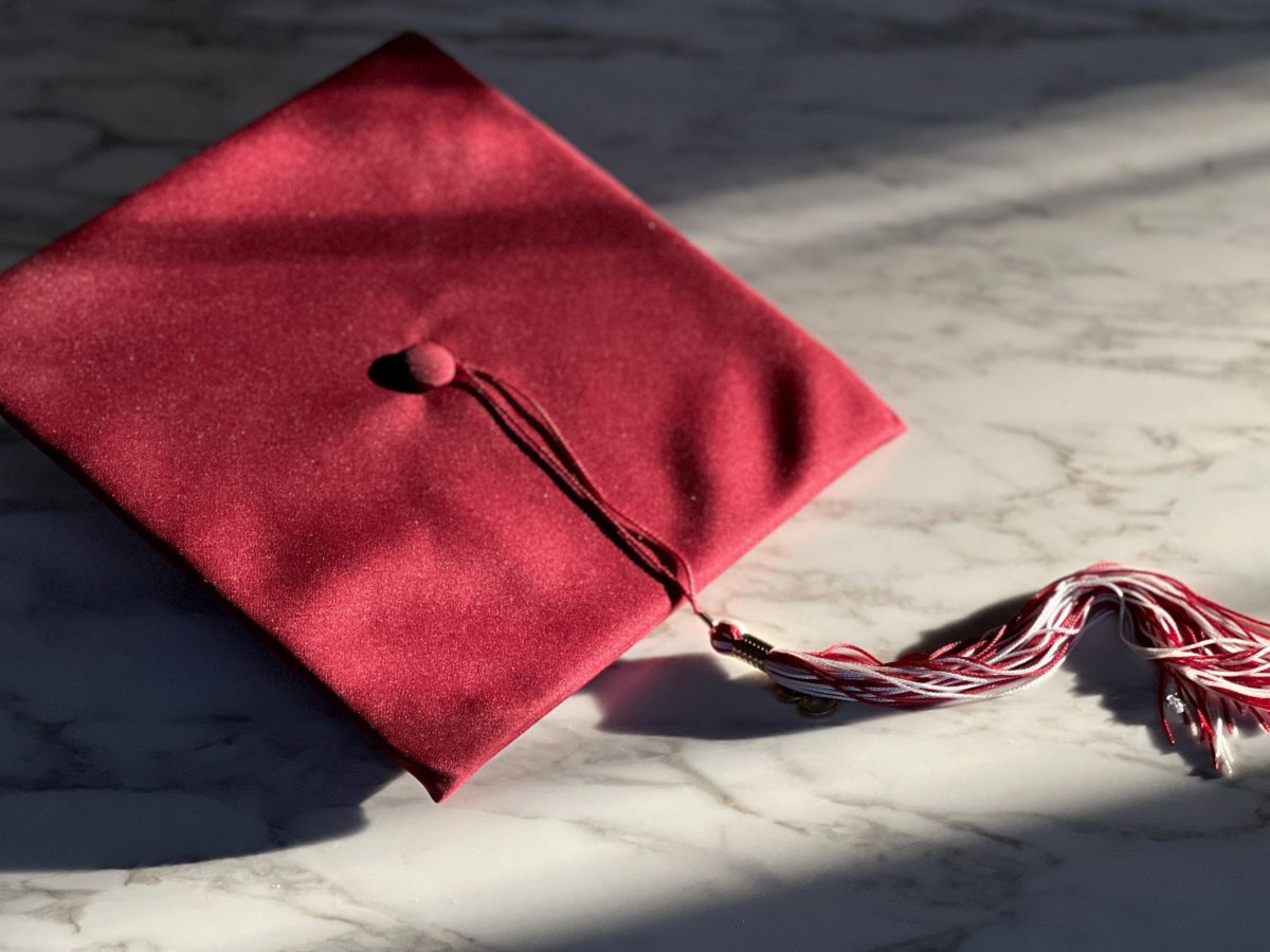 dramatic shot of a red graduation cap and tassel on marble surface