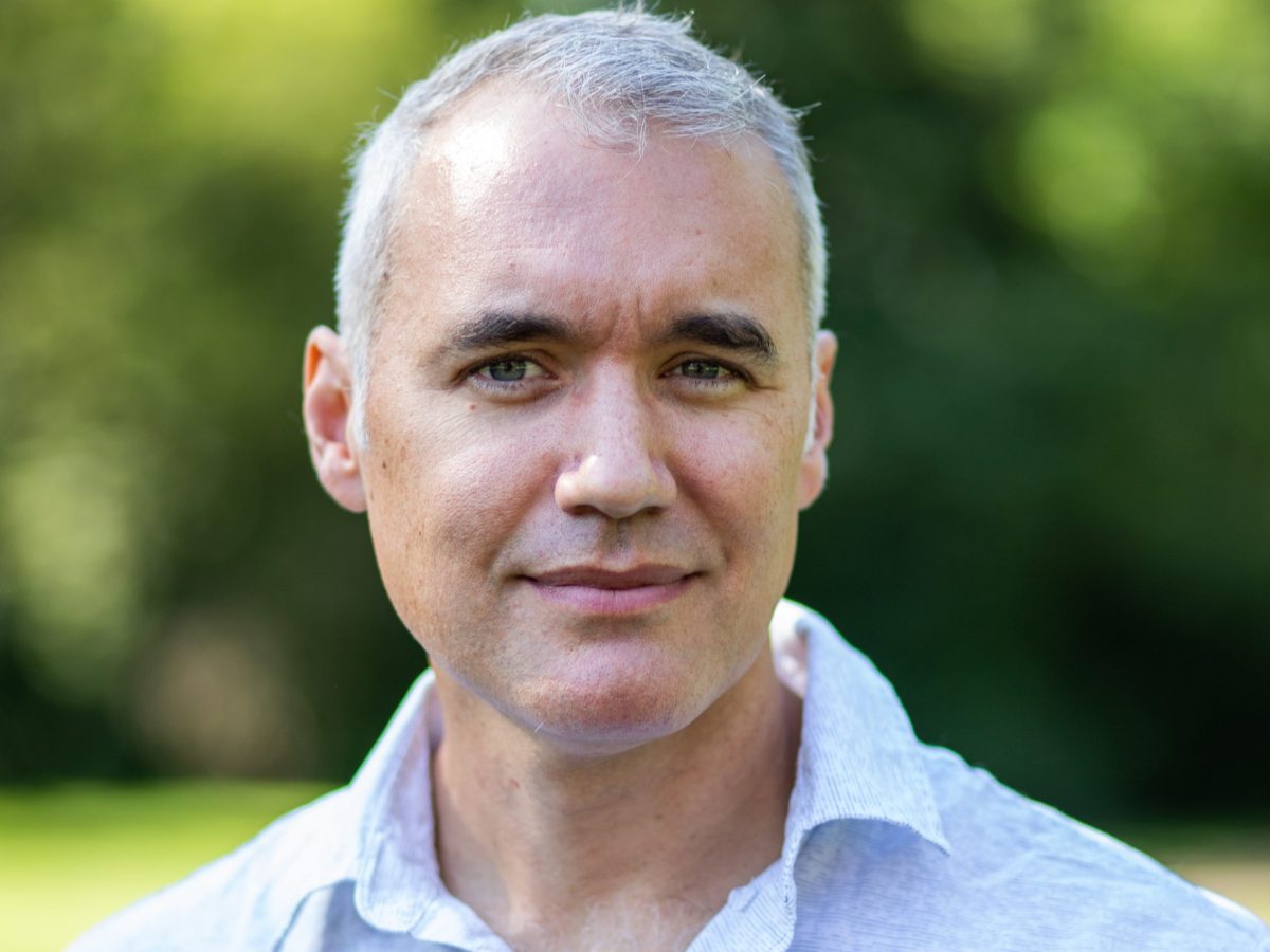 Headshot of a man with a blurred green background