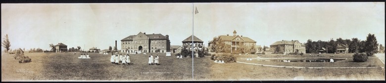 A wide, historical photo of the Mt. Pleasant Indian Industrial School in Michigan. 