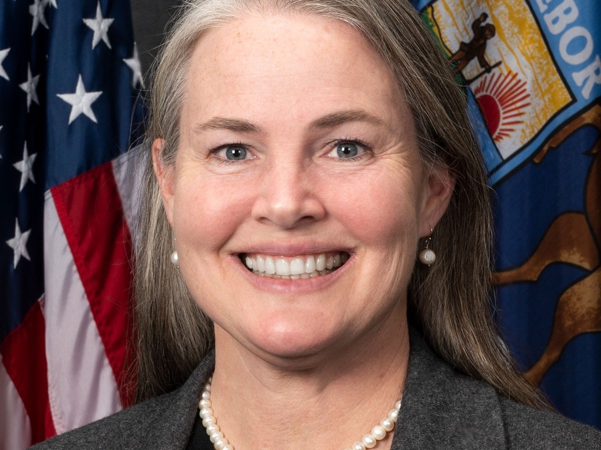 Head shot of a smiling woman in front of the US and Michigan flags