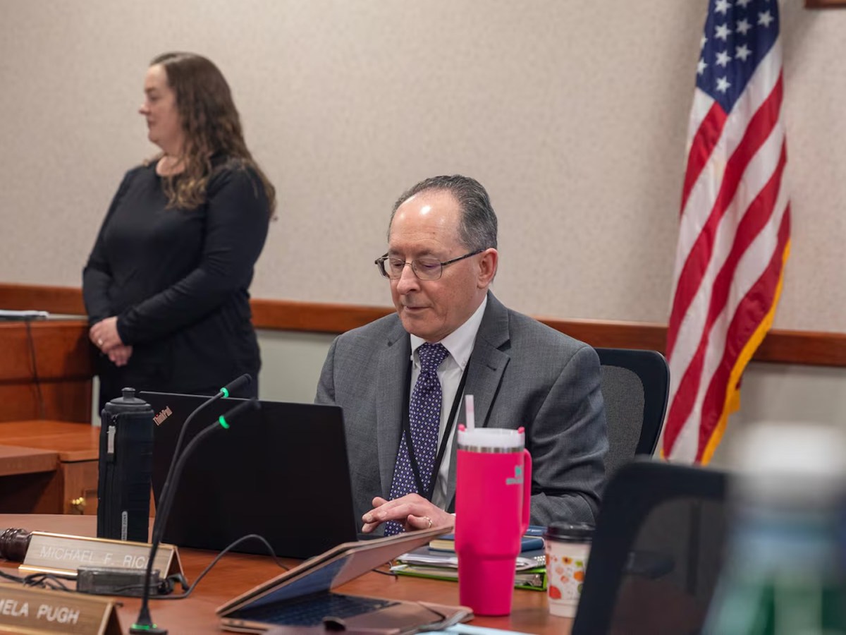 Michigan's State Superintendent Michael Rice sits at a table and looks at a laptop.