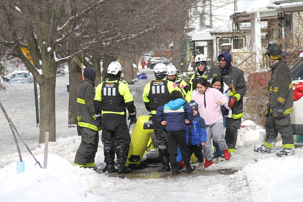Residents next to rescue crews in Detroit.