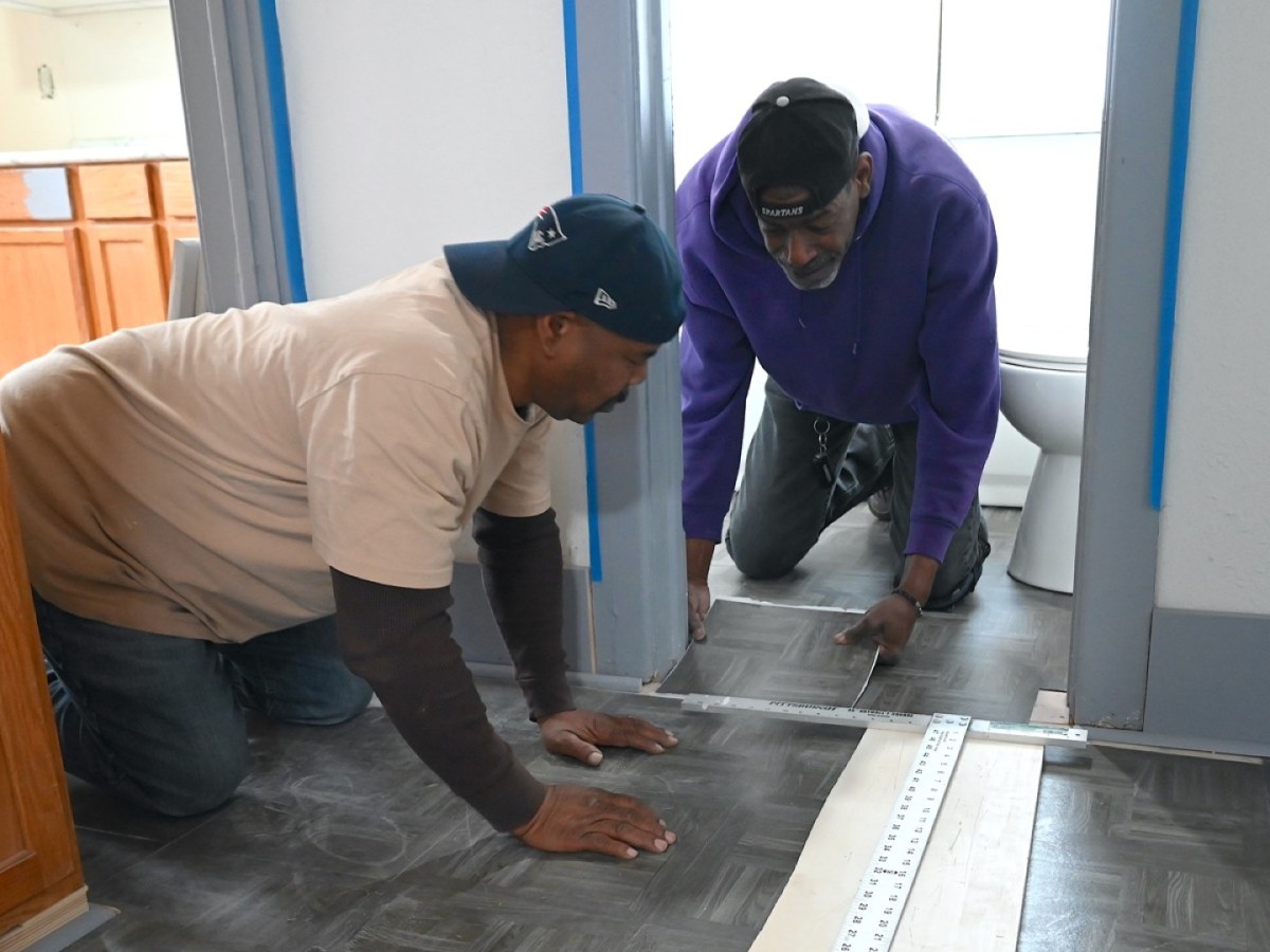 Two men install flooring