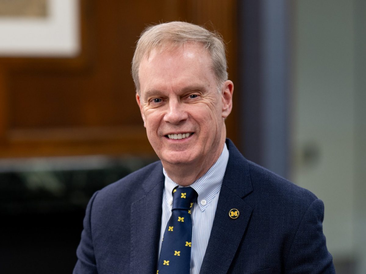 head and shoulders shot of a man in an office setting wearing a University of Michigan tie