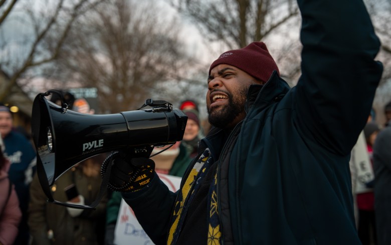 State Rep. Donovan McKinney holds a megaphone. People are behind him. 