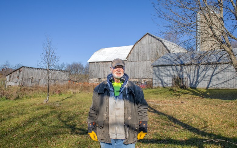 Farmer stands in front of barn and other buildings