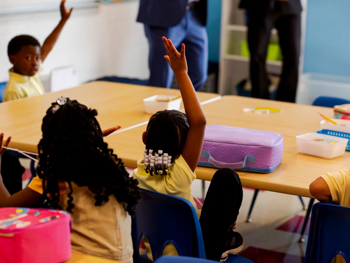Students raise their hands in a classroom. 