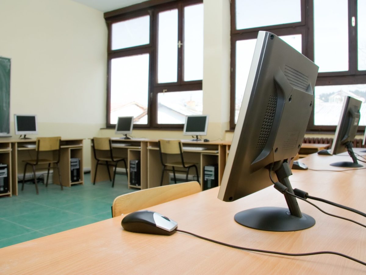 empty classroom with computer monitors on tables