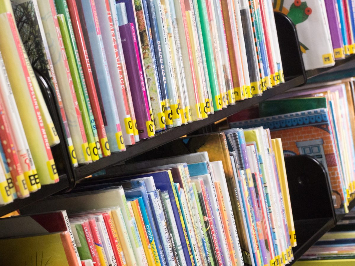 Rows of children’s books in all colors and sizes line the shelves of a children’s section. Angled view of an isolated closeup