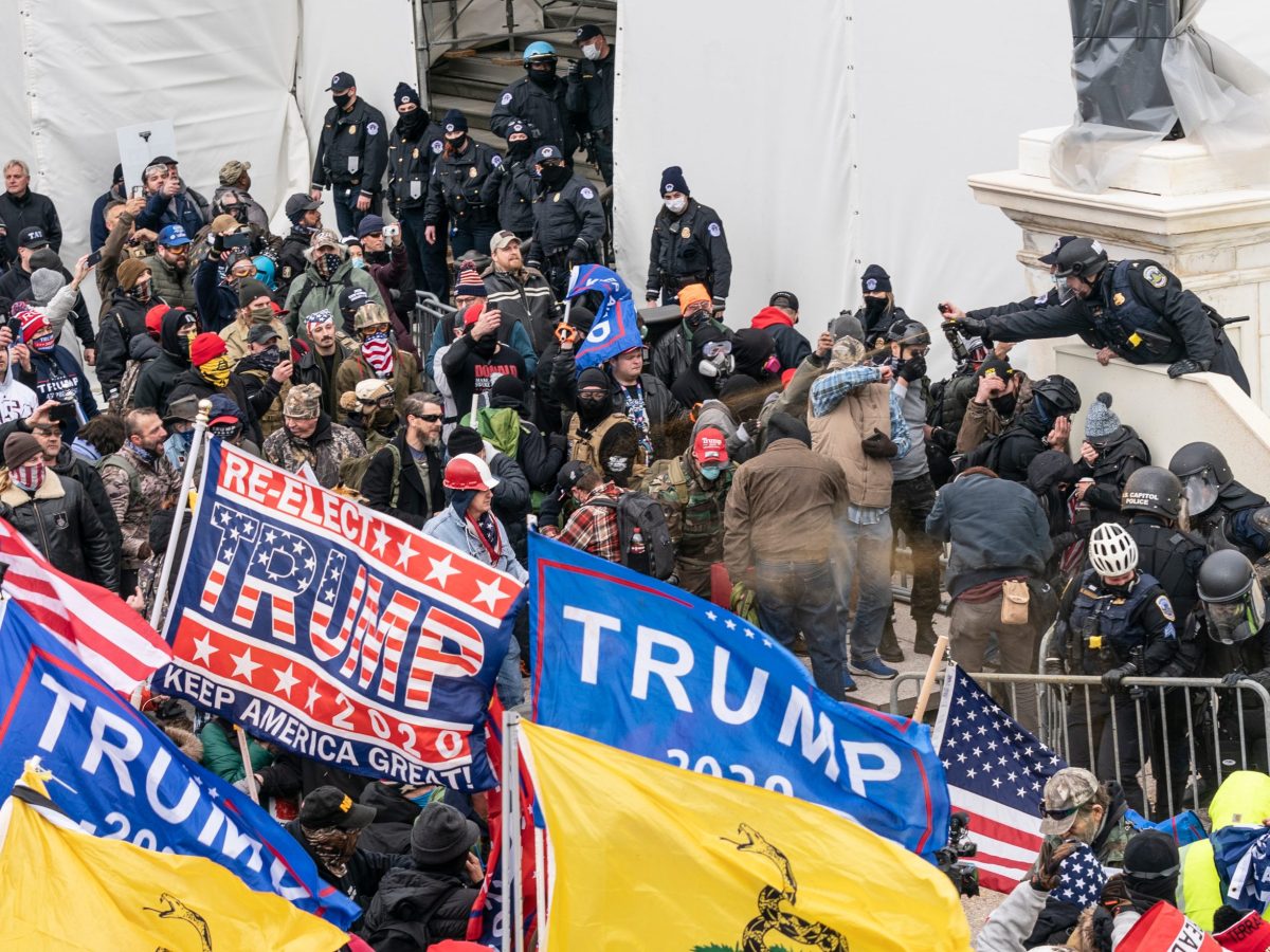 Crowds of people, many with Trump banners, confront police on the steps of the US Capitol.