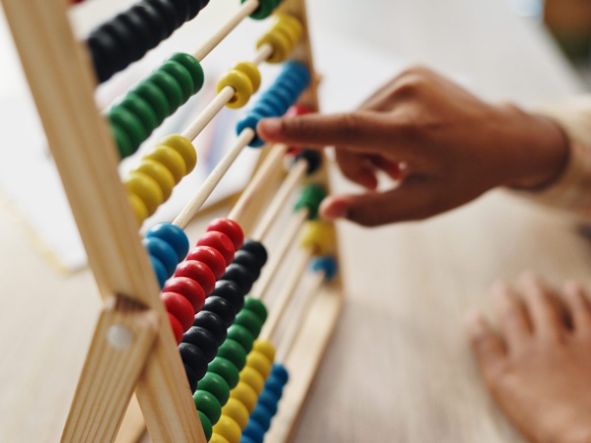 A child's hands work an abacus