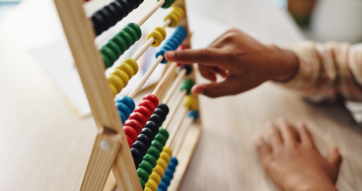 A child's hands work an abacus