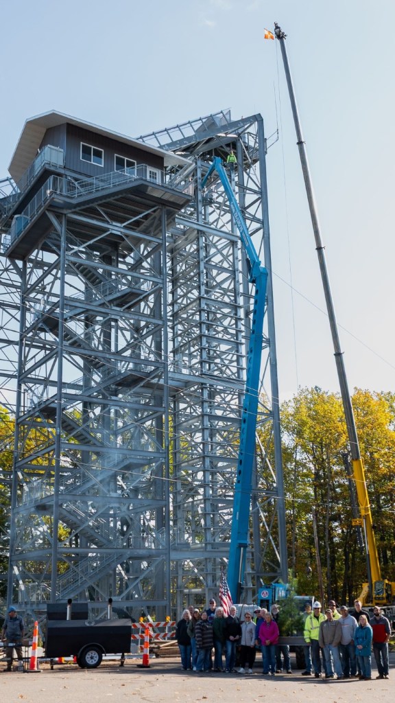 Construction workers pose next to an elevator tower under construction