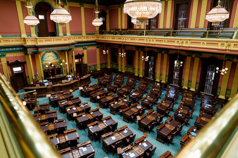 Michigan's house chamber has empty tables and chairs.