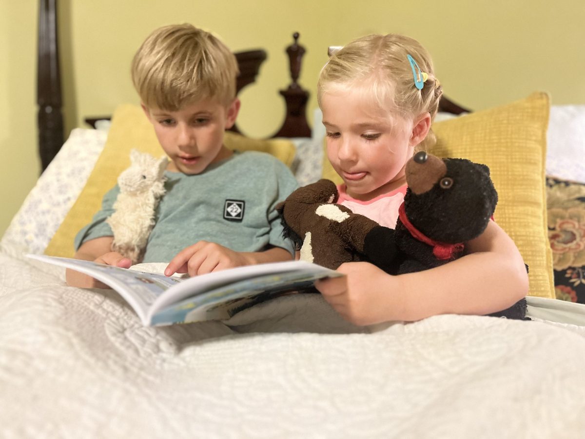 Rowan and Finn Schug are sit down next to each other, reading the same book.