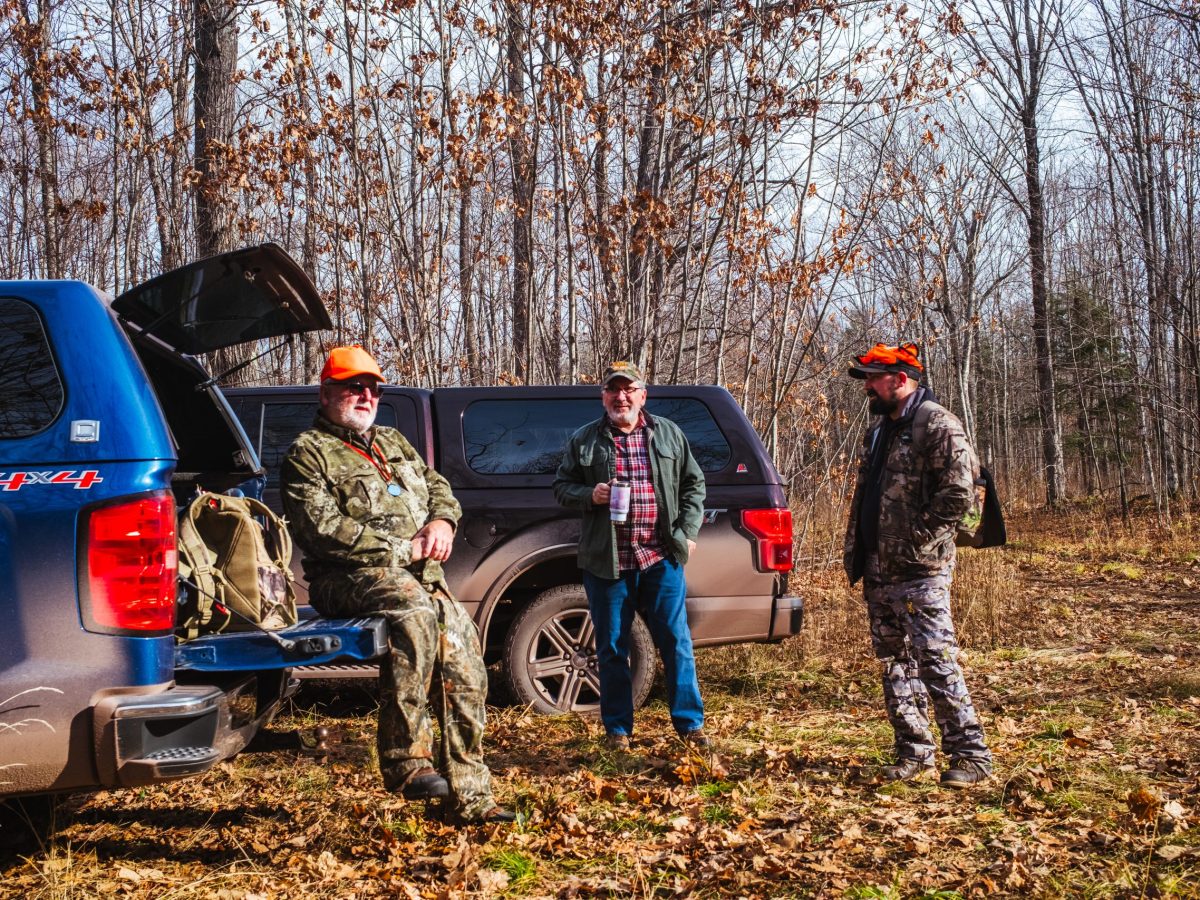 Three man stand near trucks in the woods