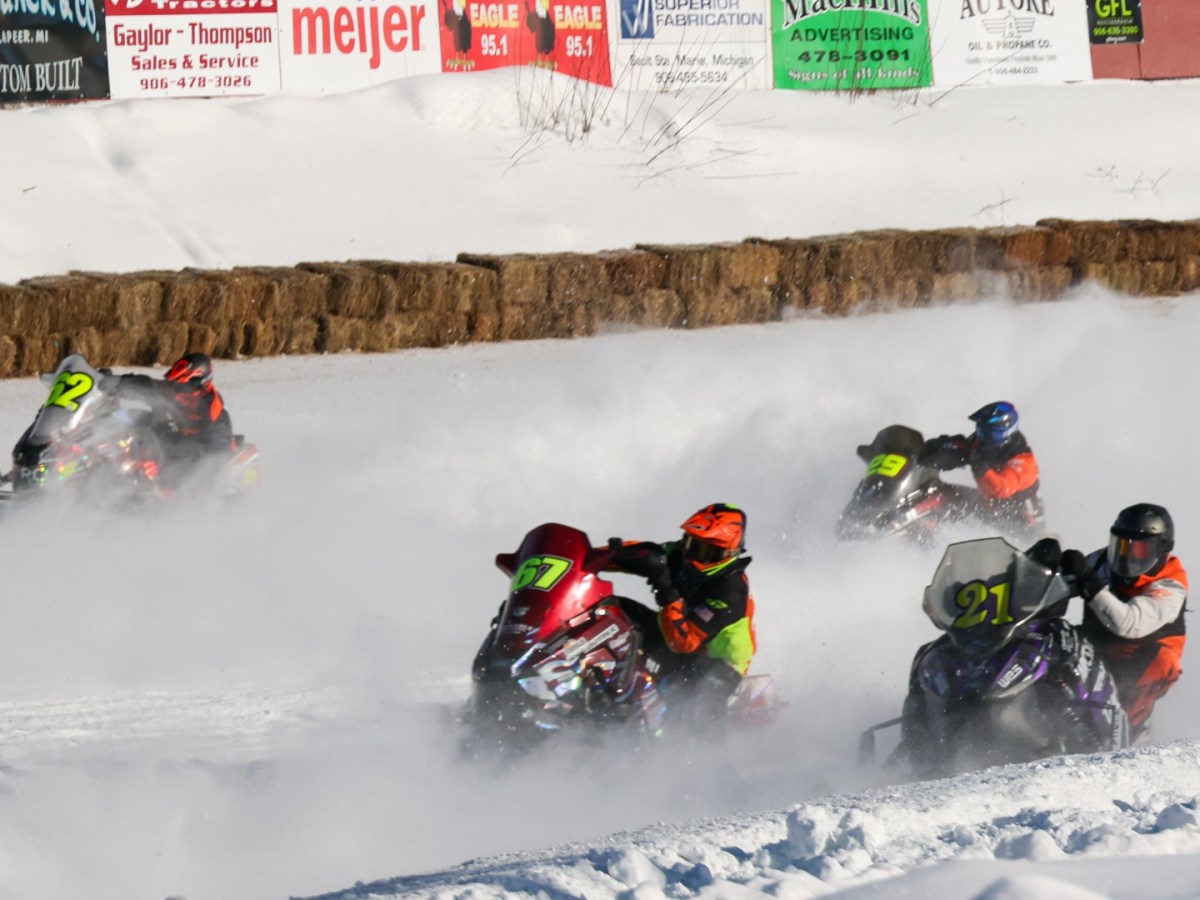 Snowmobiles race around a track