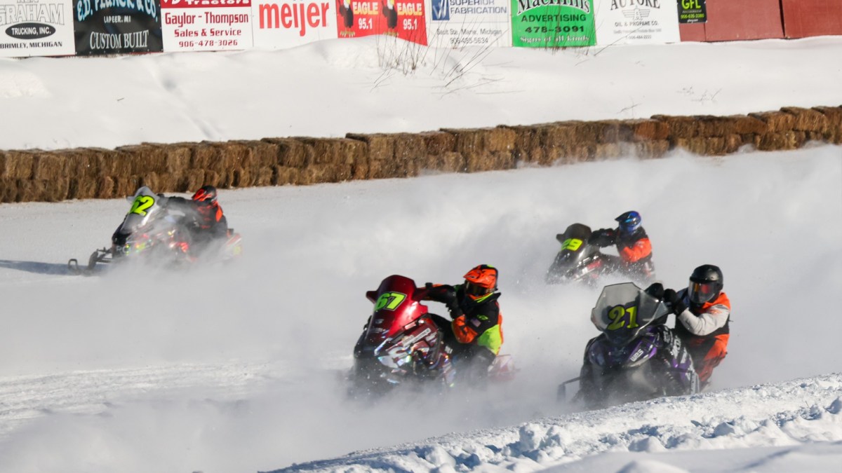 Snowmobiles race around a track