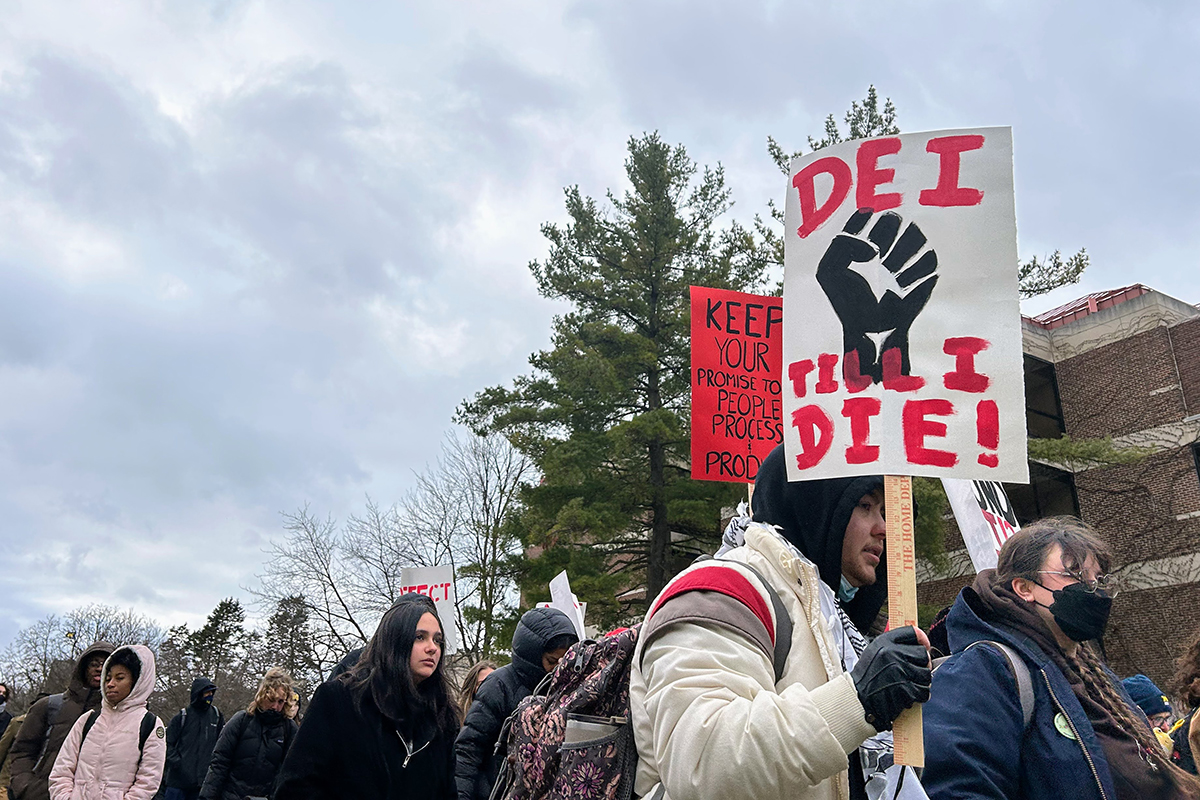 Some holding a sign that says "DEI until I die."
