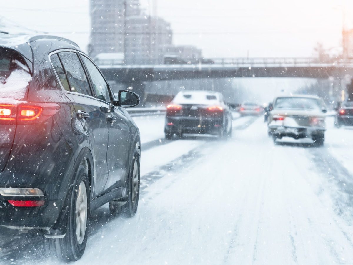 Cars drive on a snowy city street