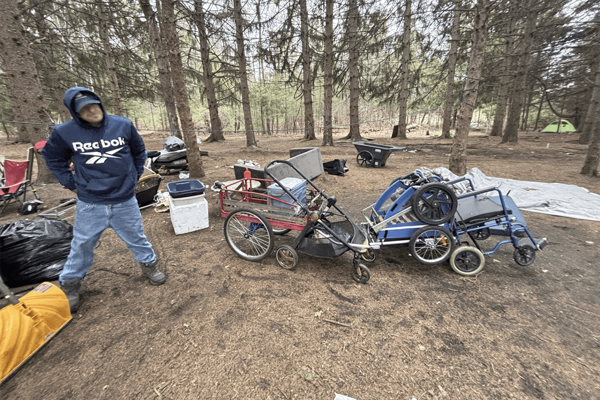 A man next to his personal items outside.