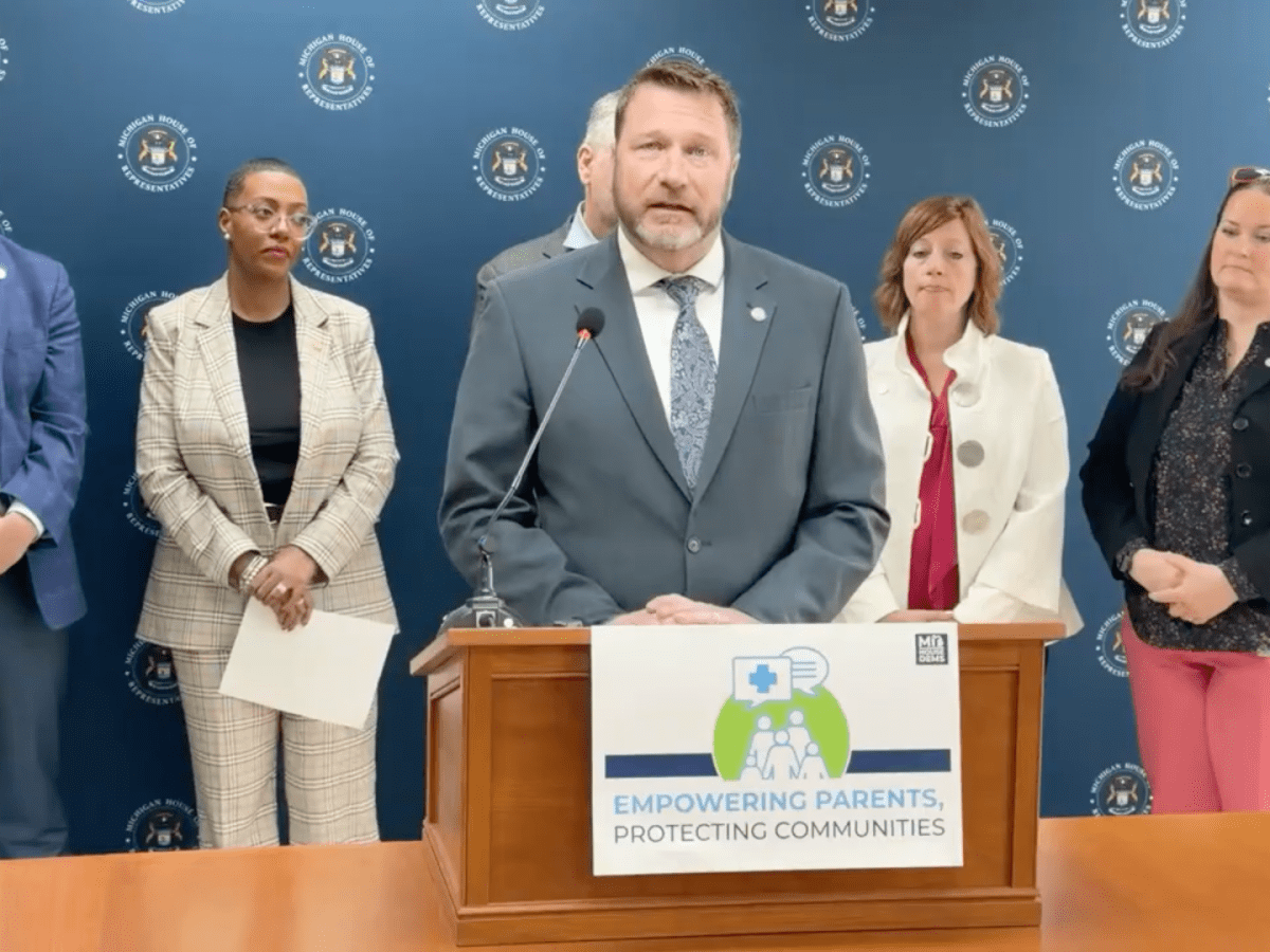 Screenshot of a group of lawmakers standing behind a podium.